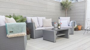 A patio with wicker furniture, a coffee table, and potted plants. - Whistler (St Ives)