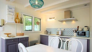 A compact kitchen with a white table, grey cabinets, and a blue-patterned backsplash. - Vouvray - Beautiful castles (Vouvray)