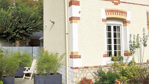 A two-story building with a beige facade and red brick accents, featuring a window with a white frame and a door. - Vouvray - Beautiful castles (Vouvray)