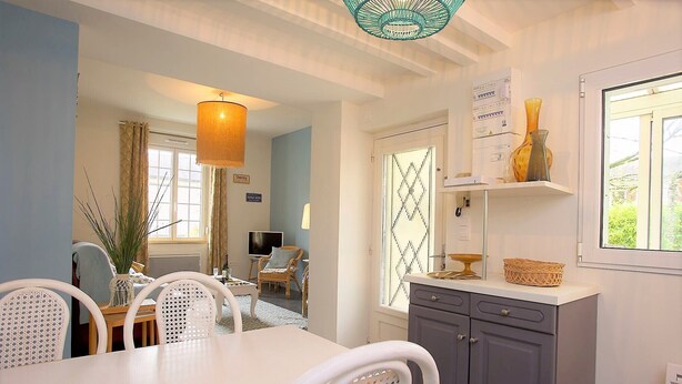A dining area with a table and chairs, a kitchen with cabinets and a window, and a hanging light fixture. - Vouvray - Beautiful castles (Vouvray)