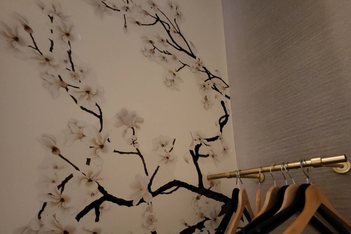 A wall with a floral design and a clothes rack.