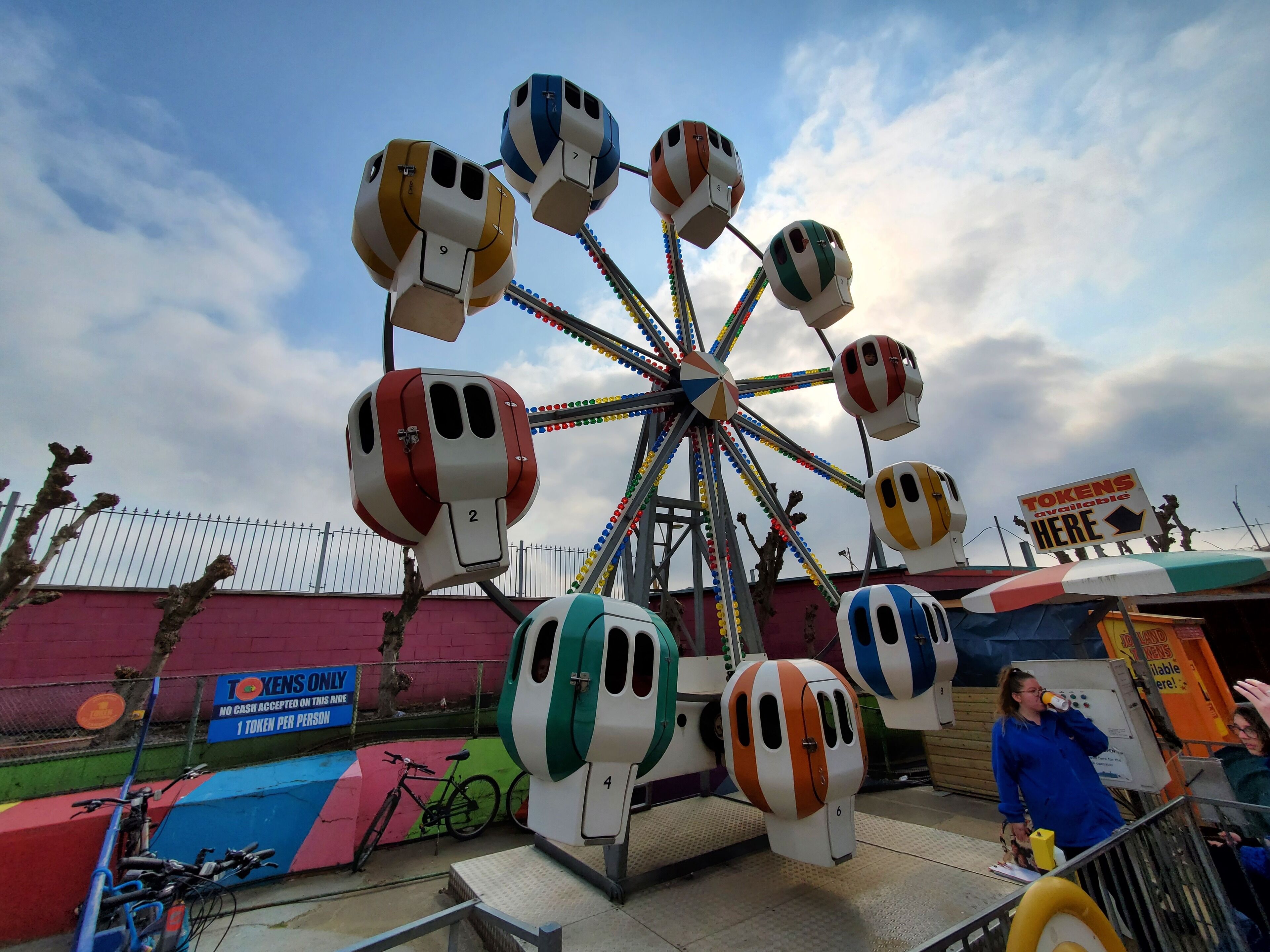 Una noria con cabinas numeradas en un parque de atracciones.