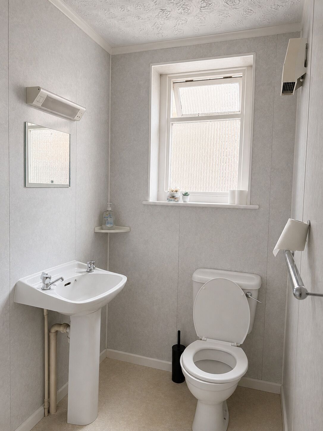 Een badkamer met een wit wastafel, toilet en raam.