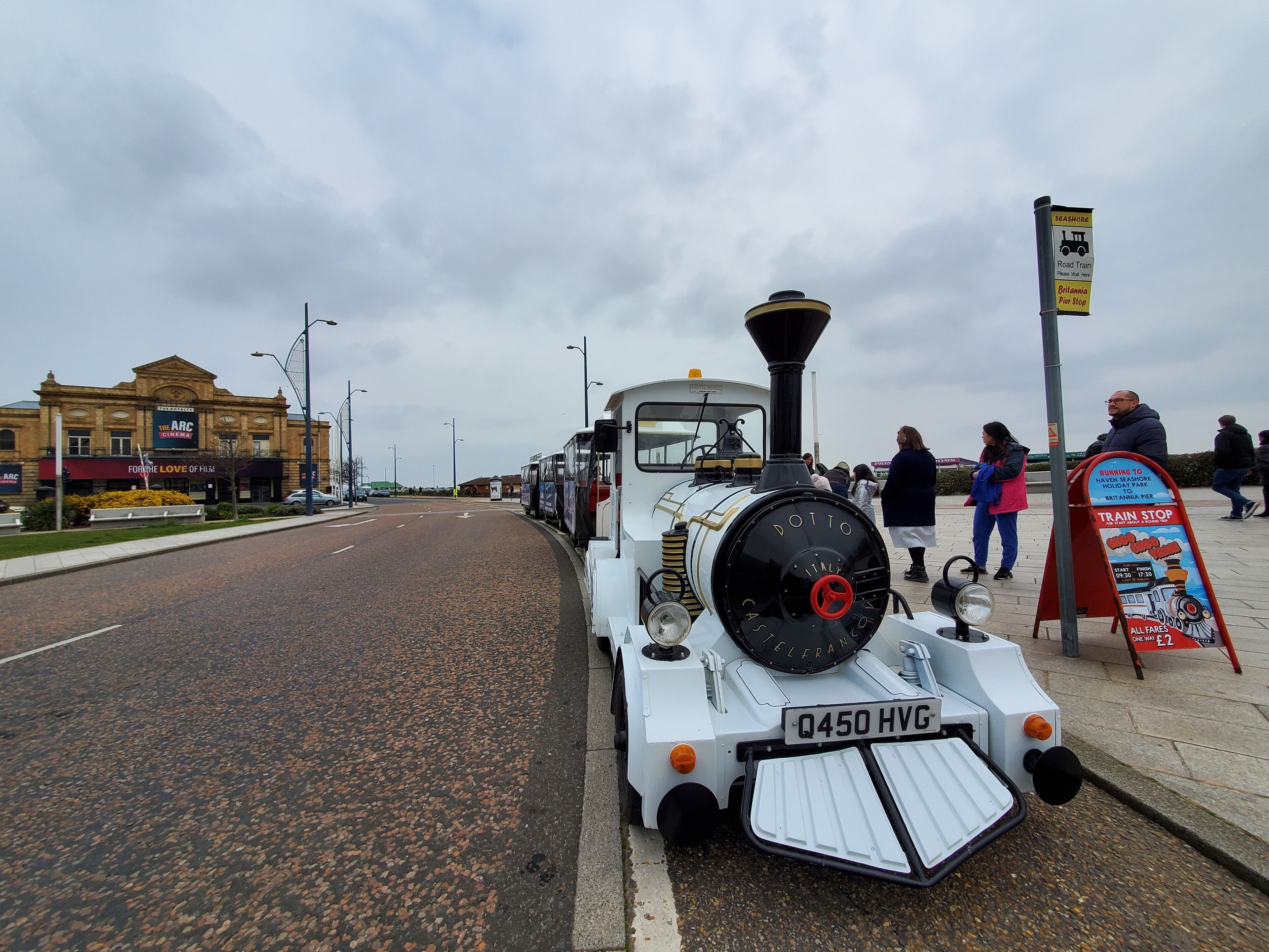 A vintage train on a track with a signboard nearby.