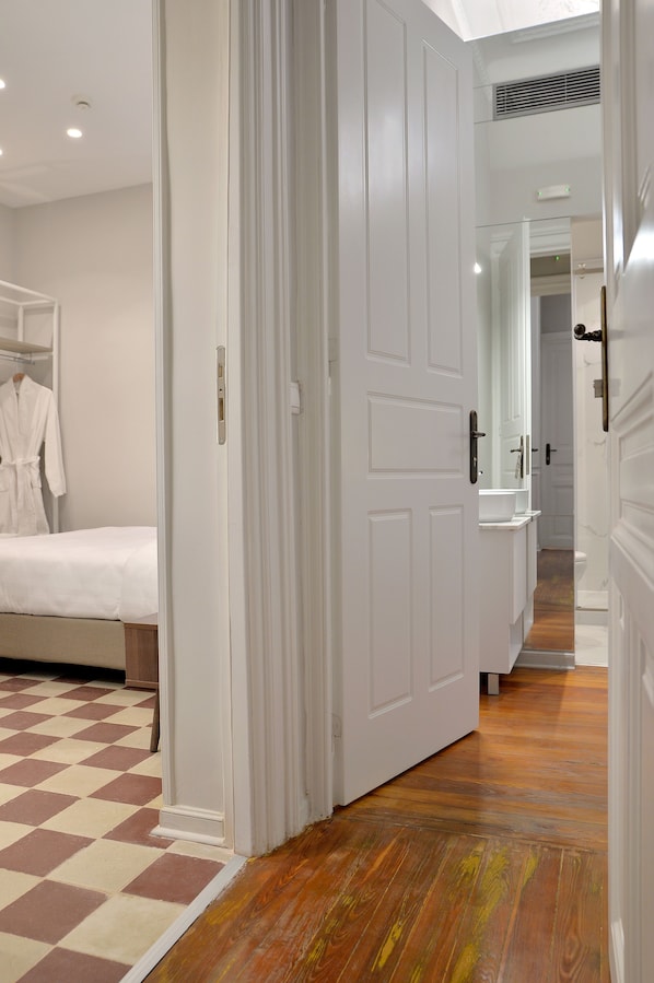 A hotel room with a checkered floor, a bed, a bathroom with a mirror, and a white door. - 1900 Athenian House (Athens)