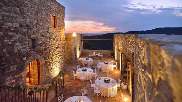 A courtyard with stone walls, round tables set for dining, and a view of the landscape in the background. - Forte Sorgnano | Farmhouse with pool (Gualdo Cattaneo(PG))