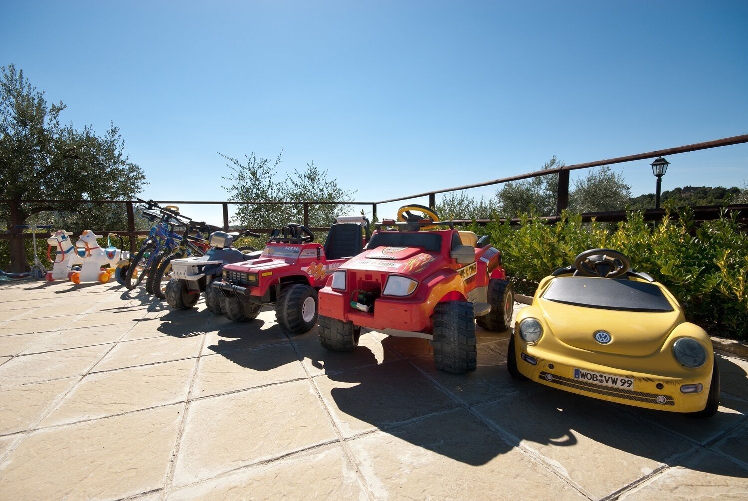 A row of toy vehicles, including a yellow VW Beetle, parked on a tiled surface.
