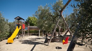 A playground with a slide, swings, and a climbing structure. - Forte Sorgnano | Farmhouse with pool (Gualdo Cattaneo(PG))