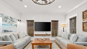 A modern living room with a large flat-screen TV, two sofas, a coffee table, and a fireplace. - 🏖Steps 2 Beach Access🏴‍☠️Pirate Themed🏝️Private Pool/Luxury/Location (Miramar Beach)