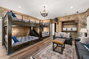 A room with a bunk bed, a sofa, a coffee table, and a chandelier.