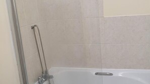 A bathroom with a bathtub, a shower, and a handrail. - Impeccable 1-bed Apartment in Ilfracombe (Ilfracombe)