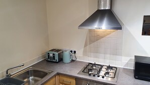 A kitchen with a gas stove, a toaster, and a sink. - Impeccable 1-bed Apartment in Ilfracombe (Ilfracombe)