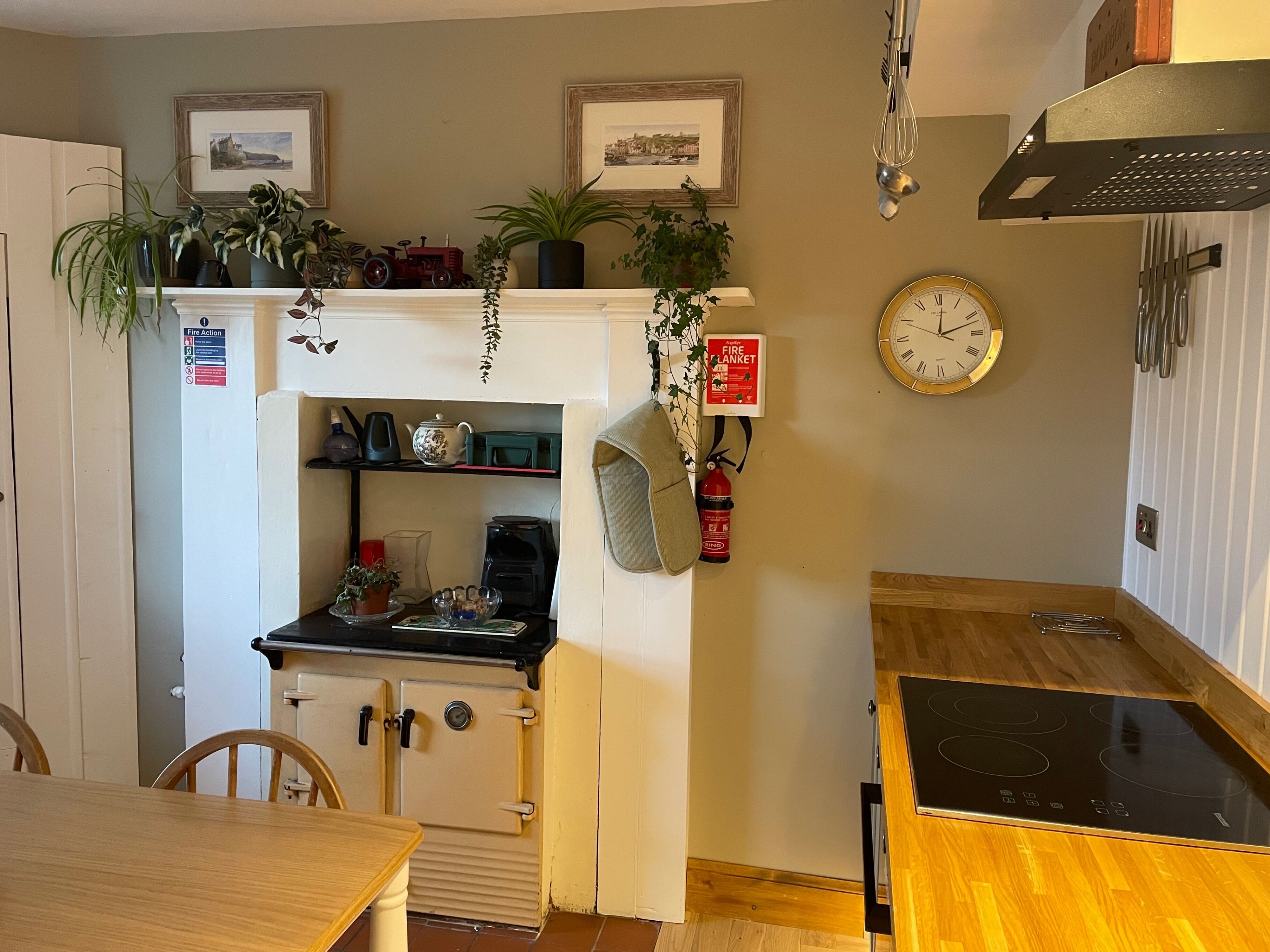 A compact kitchen with a stove, a coffee maker, and a fire extinguisher on the wall.