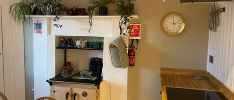 A compact kitchen with a stove, a coffee maker, and a fire extinguisher on the wall.