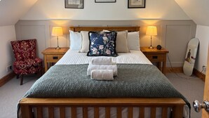 A bedroom with a bed, two bedside tables, a chair, and three framed pictures on the wall. - 1 Keepers Cottage, Skeabost Bridge, Isle Of Skye (Skeabost)