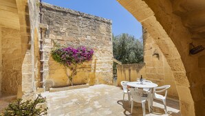 Eine Außenpatio mit Steinmauern, einem Tisch mit Stühlen und einem Blumentopf.