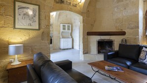 Ein Zimmer mit steinernen Wänden, einem Kamin, Ledersofas und einer gerahmten Architekturzeichnung an der Wand.