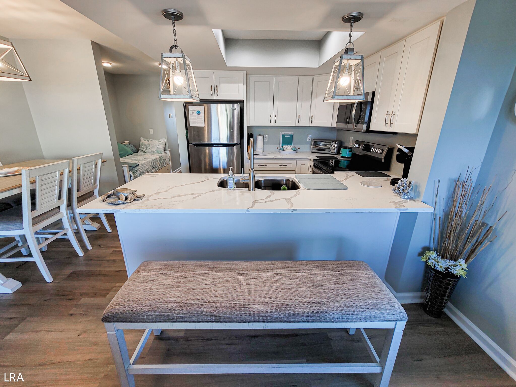 A modern kitchen with white cabinets, stainless steel appliances, and a marble island.