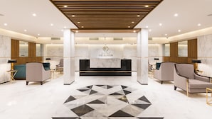 Un vestíbulo de hotel con mostrador de recepción, zona de estar y un suelo con estampado geométrico.