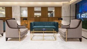 Una sala de estar moderna con un sofá color turquesa, dos sillones y una mesa de centro de vidrio.