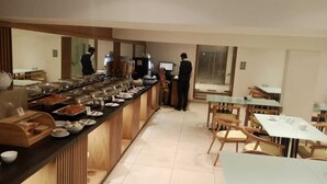 Zona de bufé con diferentes estaciones de comida, un mostrador de recepción y arreglos de asientos.