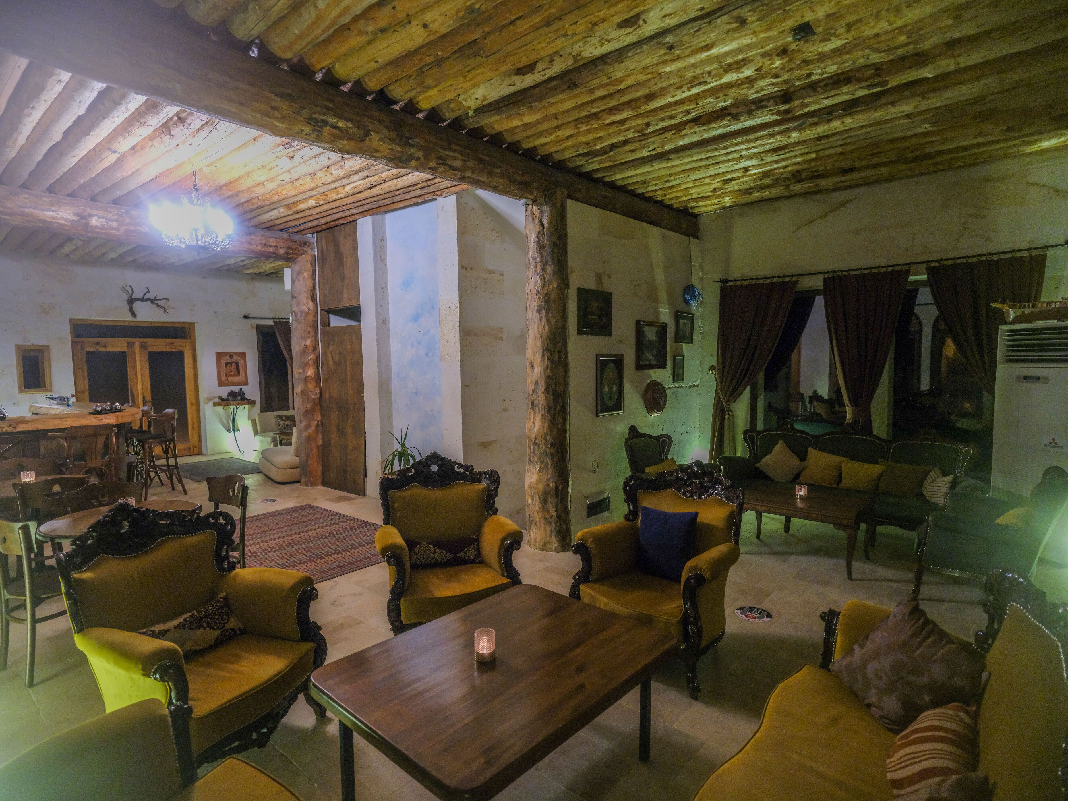 A rustic interior with wooden beams, a dining area, and seating arrangements.