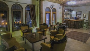 A cozy interior with wooden furniture, a bar area, and arched windows. - Kalsedon Cave Suites (Nevsehir)