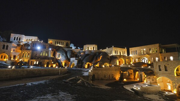 A historic building complex with multiple structures, including a prominent tower and several arched doorways. - Kalsedon Cave Suites (Nevsehir)