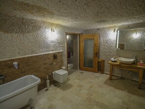 A bathroom with a bathtub, toilet, sink, and mirror. - Kalsedon Cave Suites (Nevsehir)