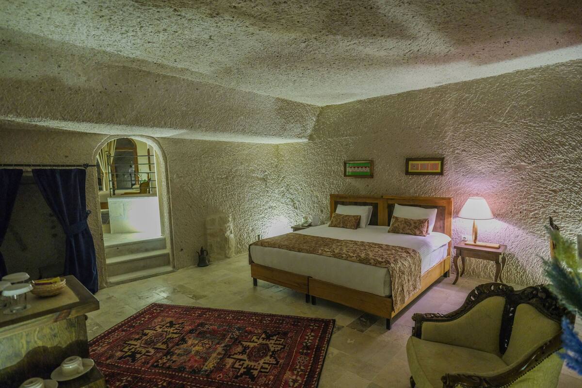 Une chambre à coucher avec un lit, une chaise, une petite table, une lampe et un tapis.