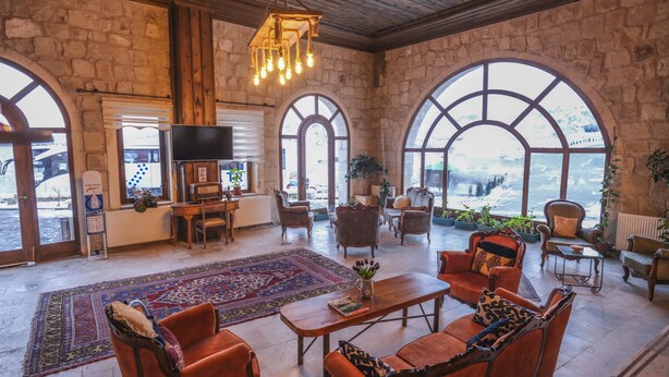 A spacious room with stone walls, large arched windows, and a wooden ceiling. - Kalsedon Cave Suites (Nevsehir)