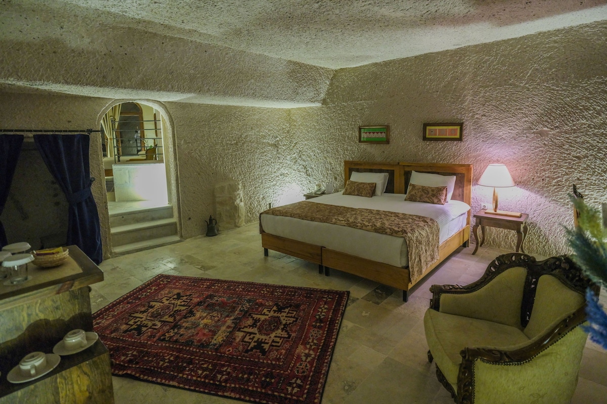 A bedroom with a bed, a chair, a small table, a lamp, and a rug.