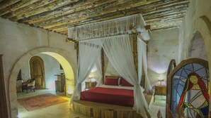 A room with a four-poster bed, a wooden ceiling, and a stained glass window. - Kalsedon Cave Suites (Nevsehir)