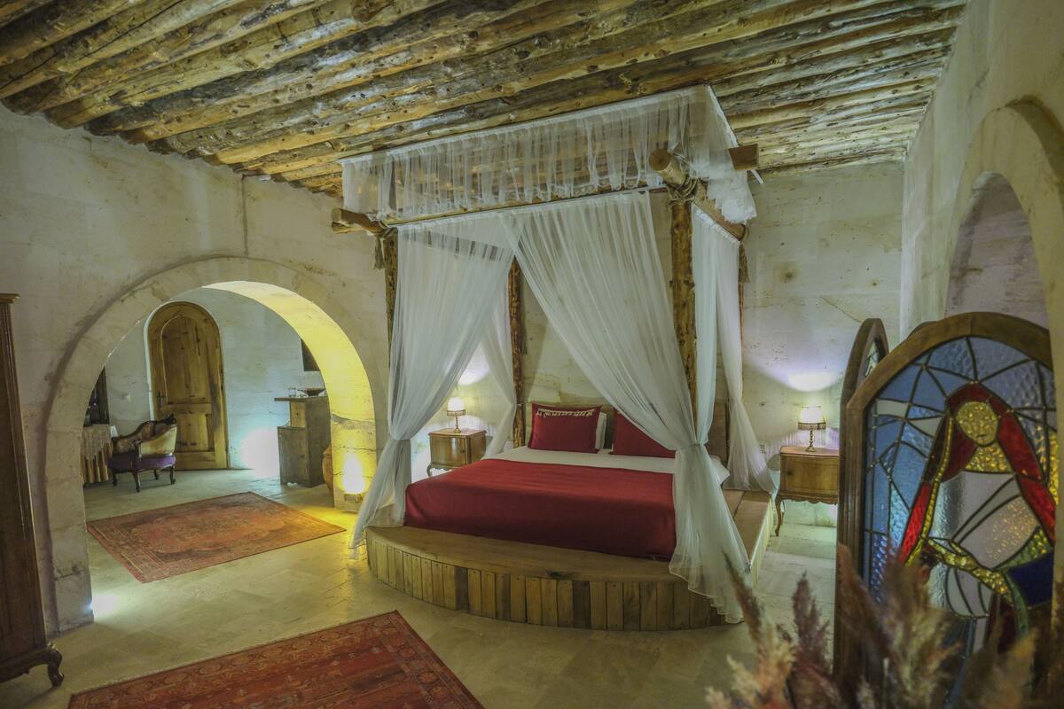 Une chambre avec un lit à baldaquin, un plafond en bois et une fenêtre à vitraux.