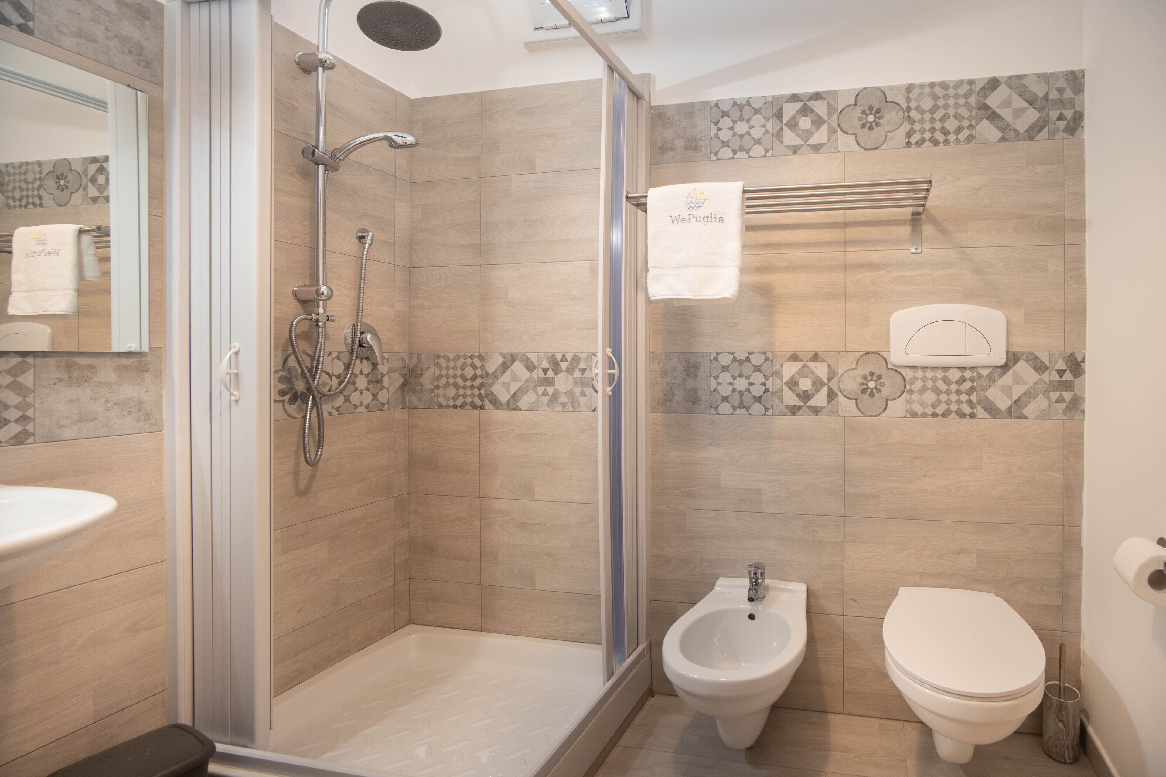 Un bagno moderno con doccia vetrata, un bidet, un water e un lavandino.