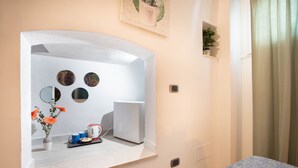 Un baño moderno con un espejo integrado, un lavamanos pequeño y un inodoro. Hay una planta en la pared y una cortina de ducha.