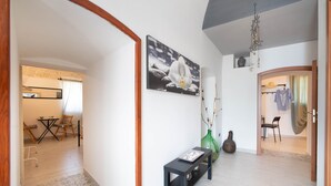 Un pasillo con un banco, un florero y un cuadro en la pared.