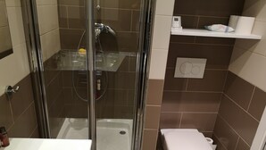A bathroom with a glass-enclosed shower, a white toilet, and a white sink. - 1 Bedroom Apartment in Fresnes (Fresnes)