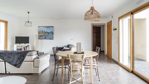 Un soggiorno moderno con un tavolo da pranzo, sedie, un divano, una TV e un quadro appeso al muro.