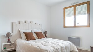 Una camera da letto con una testiera in legno, un letto con biancheria bianca, due comodini con lampade e una finestra con persiane.