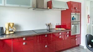 Una cucina moderna con pensili rossi, un forno in acciaio inossidabile e una macchina per il caffè sul bancone.
