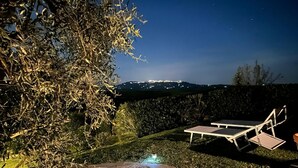 Eine Außenpatio-Terrasse mit einem Kiesweg, zwei weißen Liegestühlen und einem kleinen Tisch.