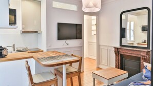 Un salon moderne doté d’une cheminée, d’un téléviseur et d’un coin repas avec une table et des chaises.