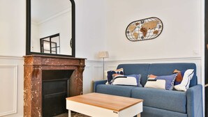 Un salon avec un canapé bleu, une table basse en bois, une cheminée et une décoration murale représentant une carte du monde.