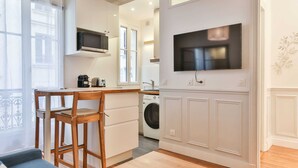 Une cuisine compacte équipée d’un four à micro-ondes encastré, d’un lave-linge et d’un téléviseur fixé au mur.