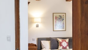 Une chambre à coucher avec un lit, une table de chevet, une lampe fixée au mur et un tableau encadré accroché au mur.