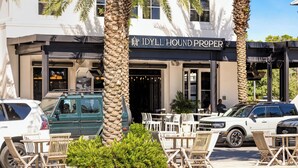 Een restaurant met terras, palmbomen en een bord met de tekst 'IDYLL HOUND PROPER'.