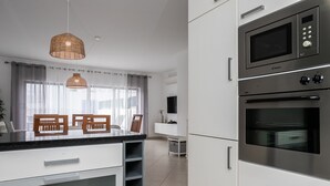 Une cuisine moderne avec des meubles blancs, un four à micro-ondes encastré et un grand îlot central doté d’un plan de travail noir.