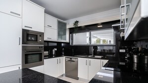 Une cuisine moderne dotée d’appareils électroménagers en acier inoxydable, de meubles blancs et d’un plan de travail en granit noir.