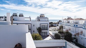 Un quartier résidentiel en bord de mer, avec des immeubles modernes aux façades blanches, dont certains sont dotés de panneaux solaires, et qui offre une vue dégagée sur la mer.